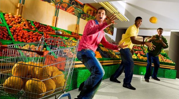 Tre giocatori giocano con la frutta in un supermercato